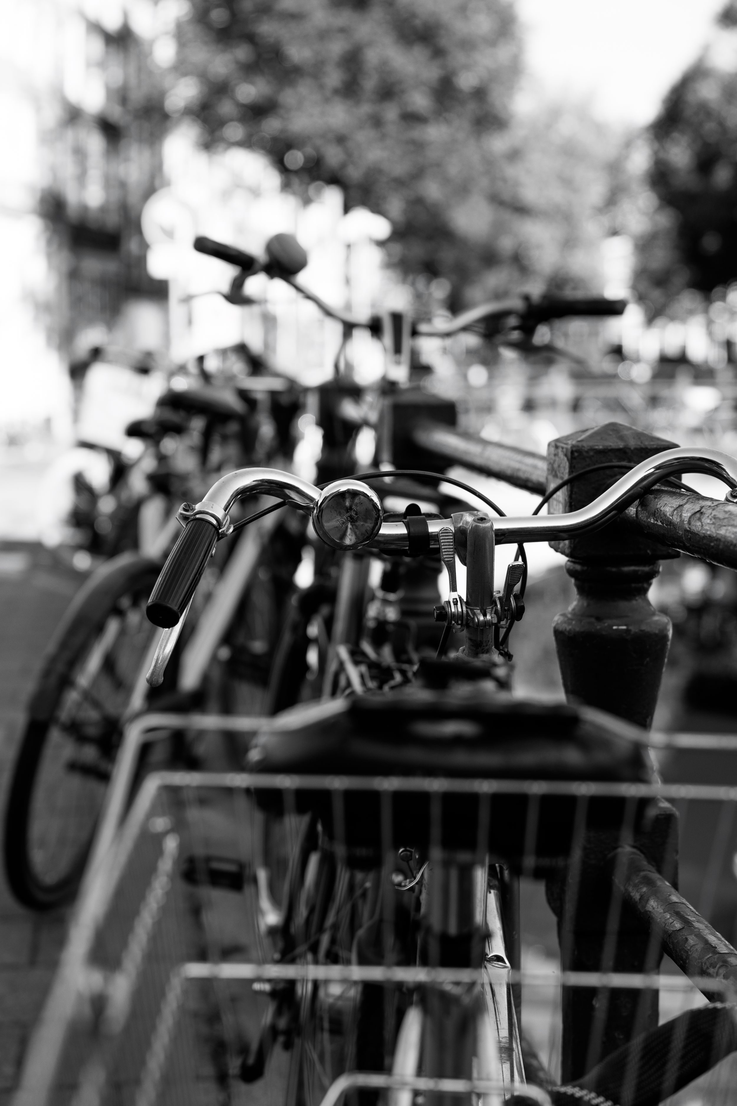 Close-up black and white image of bicycle handlebars parked in a bike rack.