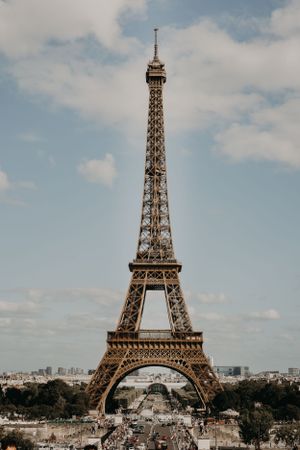 Iconic Eiffel Tower standing tall against a cloudy Parisian sky with city buildings in the background.