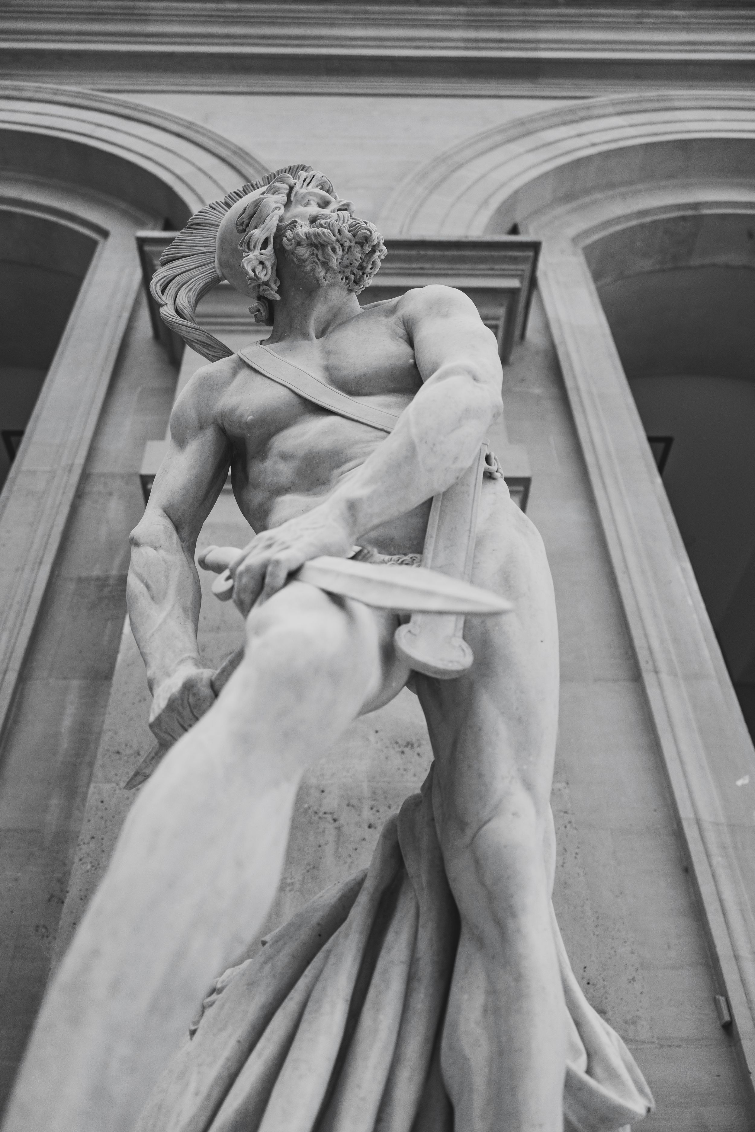 A dramatic classical marble statue with flowing drapery photographed from below.