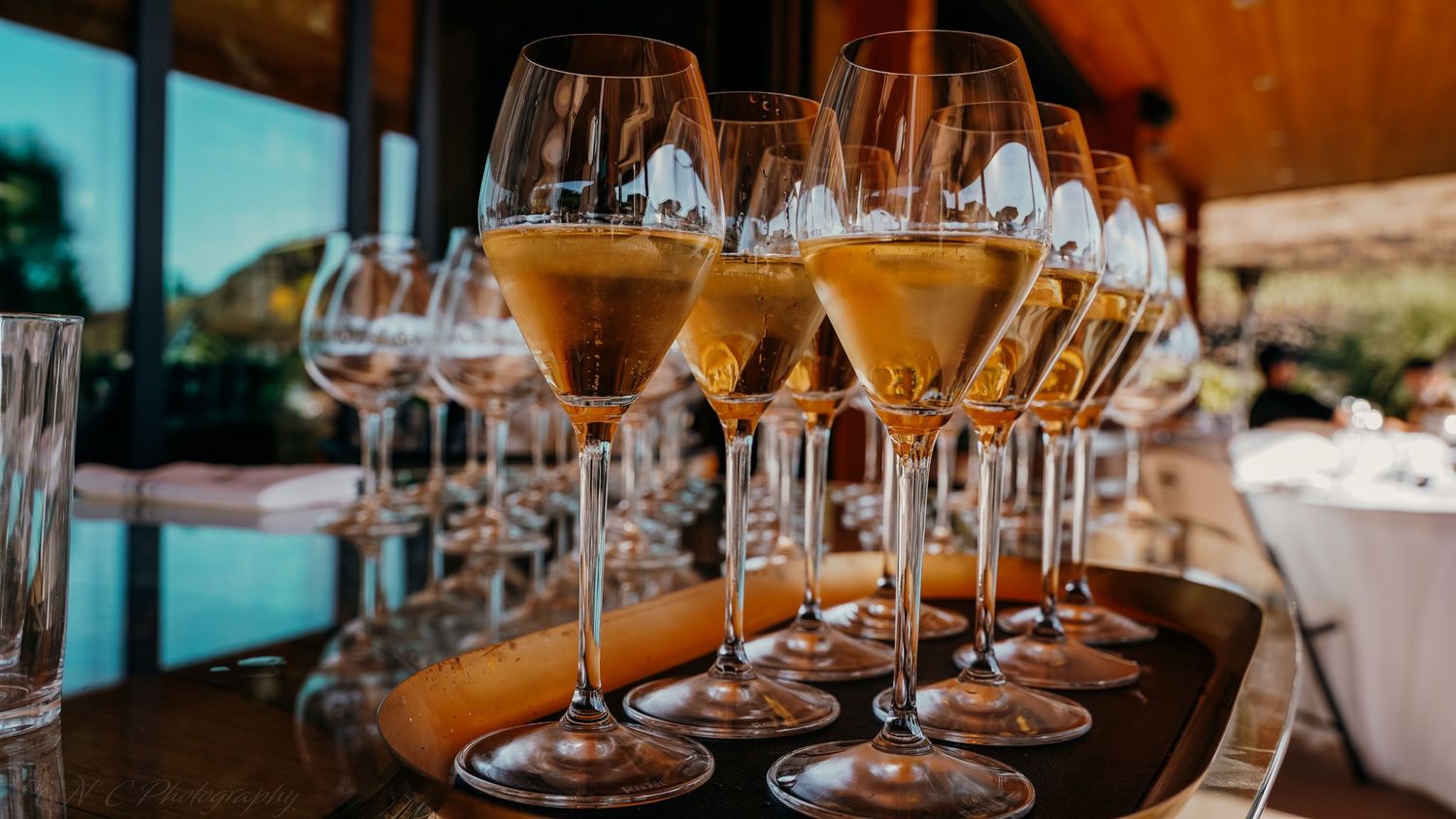 Multiple champagne glasses filled with golden bubbly arranged on a wooden serving tray.