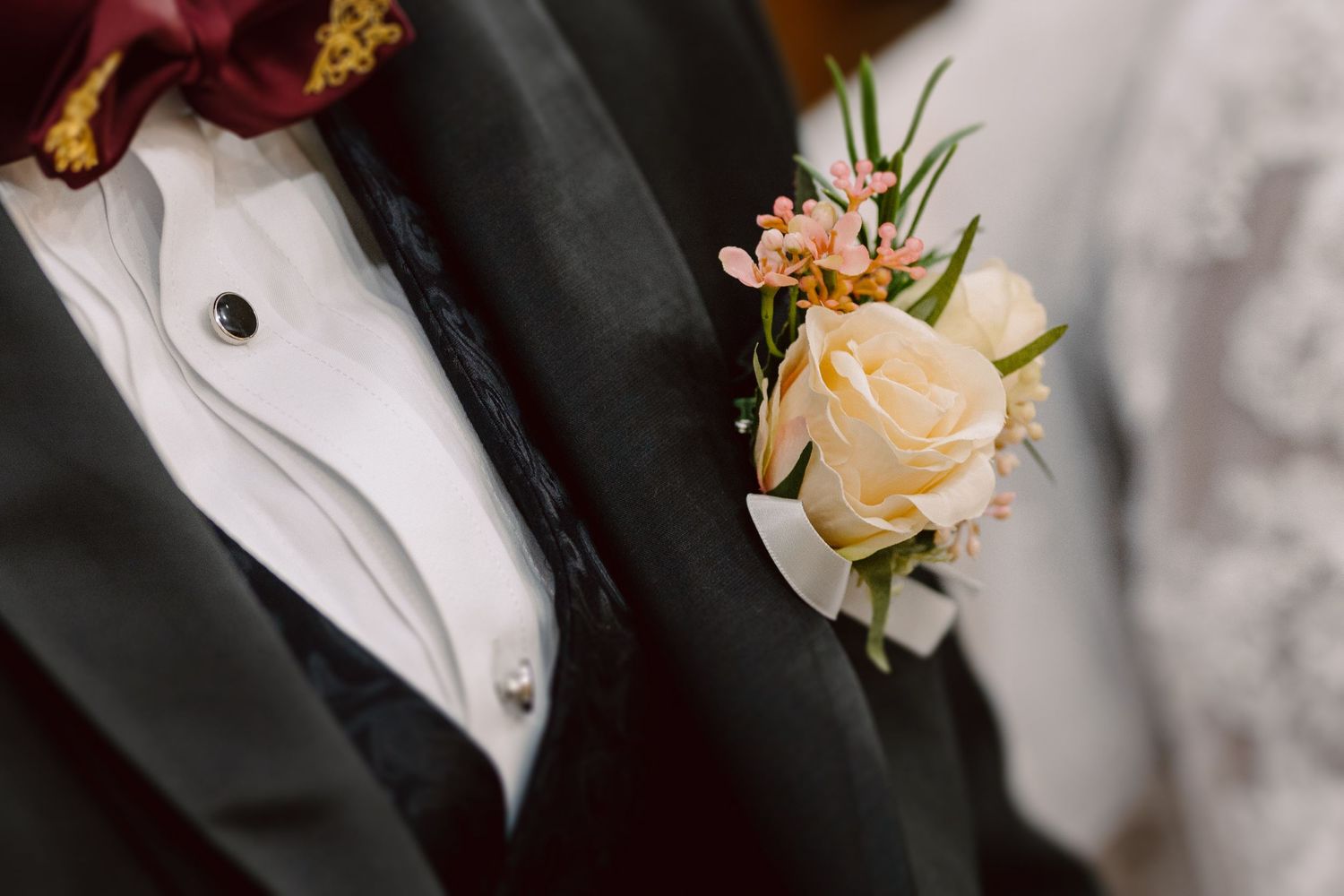 Close-up of peach rose boutonnieres on formal black suits.