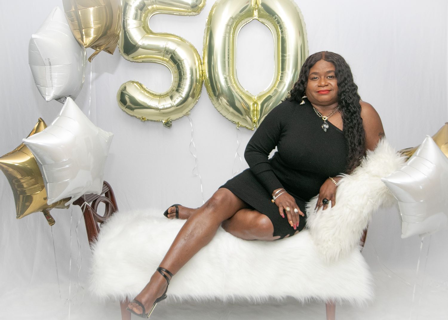 Elegant birthday photo shoot with gold 50 balloons and white star decorations.