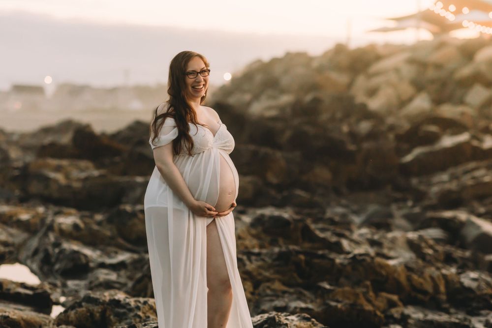 First time mom cradling pregnant belly during maternity photoshoot in York Beach, Maine