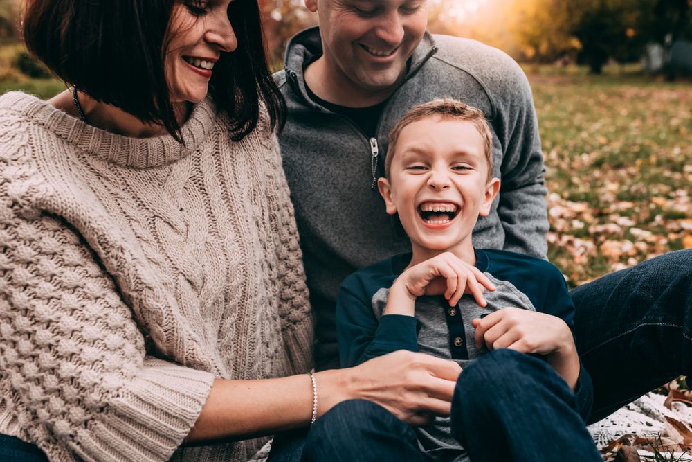 Mom, dad, and young boy laughing during fall family photoshoot in Medford, MA