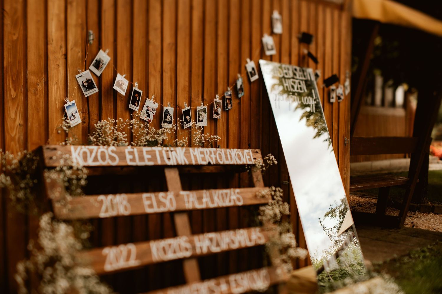 Rustic wooden signs with string lights hanging on a wooden deck railing at dusk.