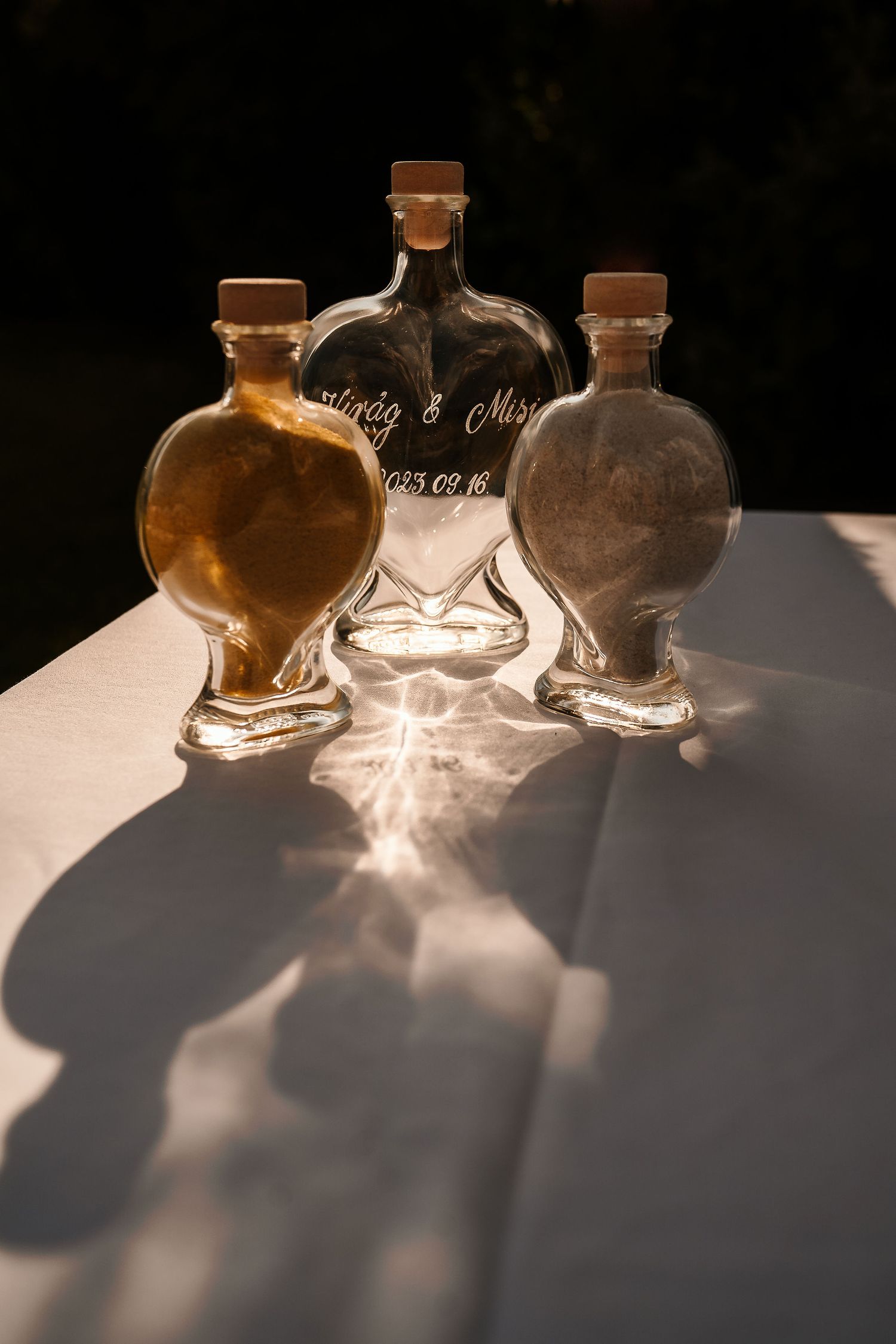 Three decorative glass bottles with custom etching captured in dramatic lighting.