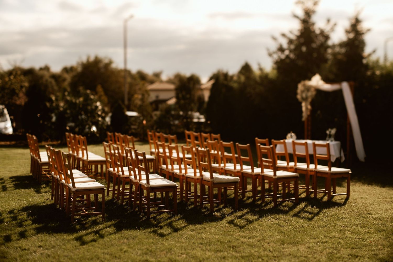 Rows of wooden chairs set up on lawn for outdoor wedding ceremony.