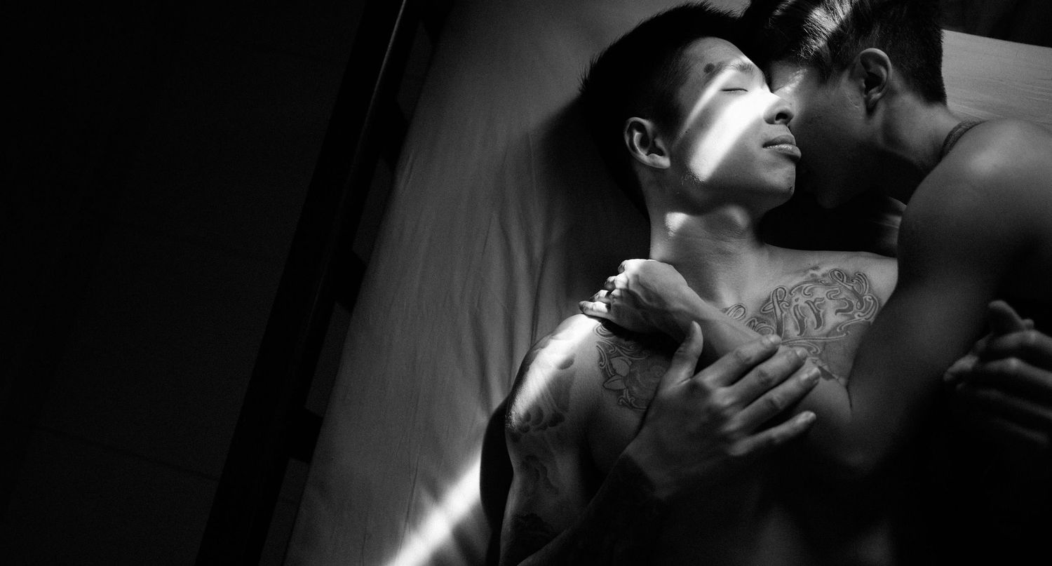 couple with tattoo cuddle on bed.
