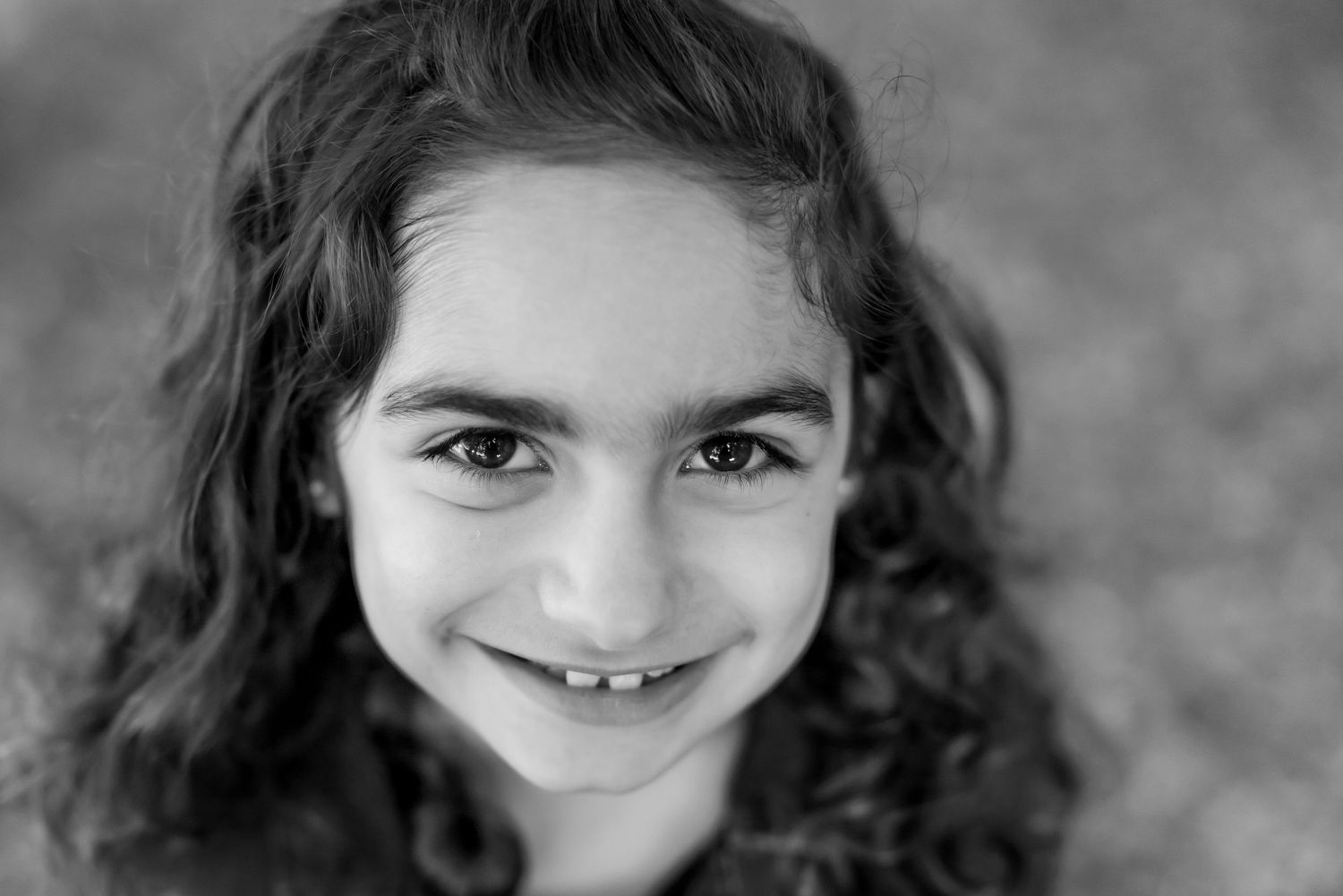 Close up portrait showing a gentle smile against a black and white background.