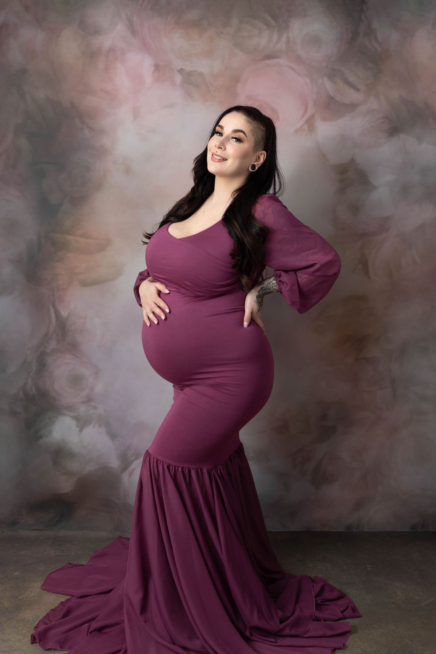 Elegant gravidposering I en burgunder gravidkjole med puffermer med blomstrete drømmende bakgrunn fotografert i studio ved Lillestrøm