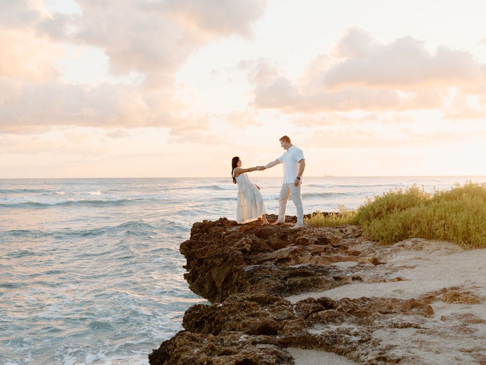 A couples photoshoot by Moments With Kell on Oahu in Hawaii with husband and wife dancing on the beach