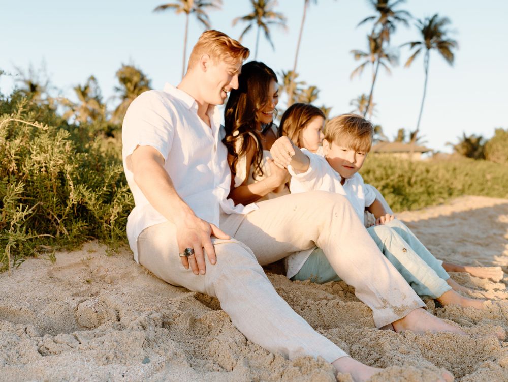 A family photoshoot by Moments With Kell on Oahu in Hawaii with family sitting on the beach