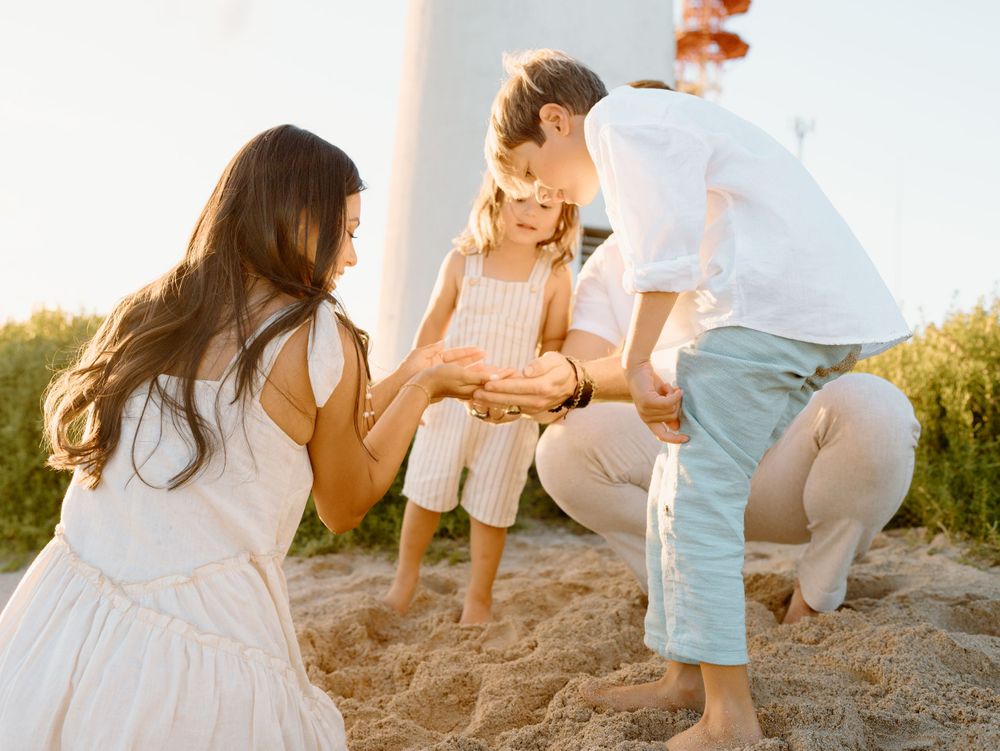 A family photoshoot by Moments With Kell on Oahu in Hawaii looking at shells on the beach