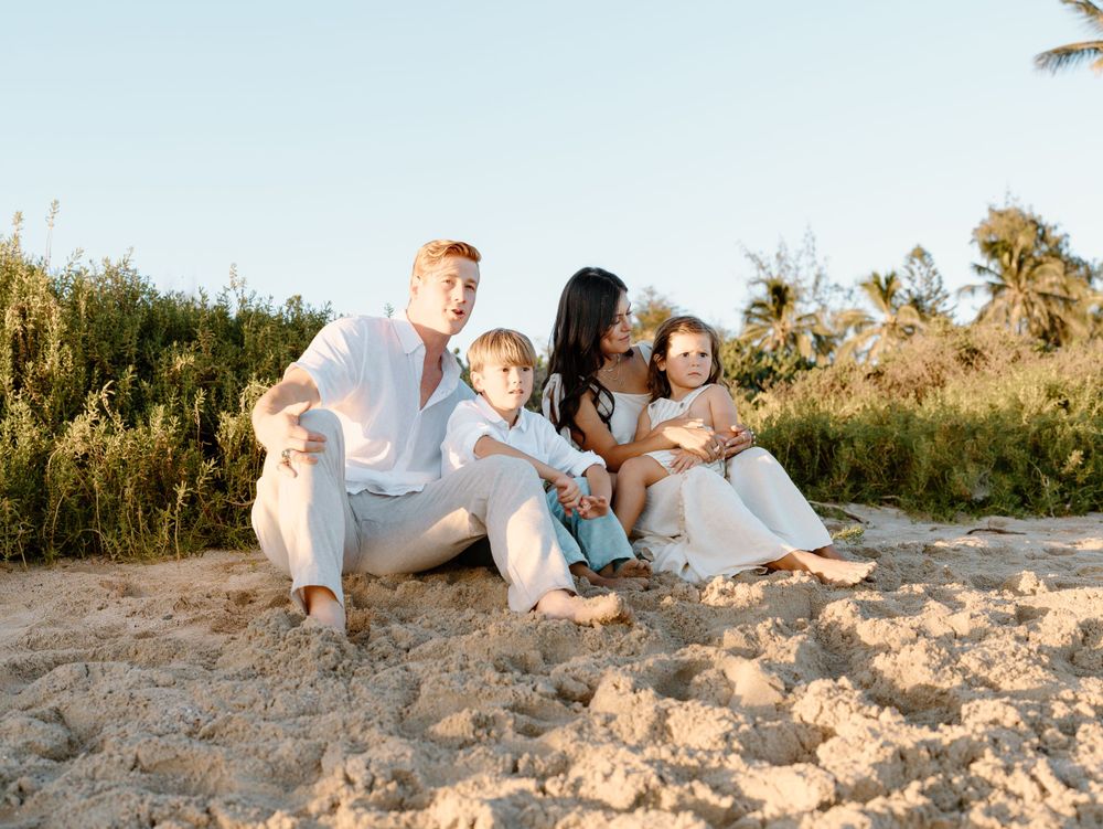 A family photoshoot by Moments With Kell on Oahu in Hawaii with family sitting on the beach