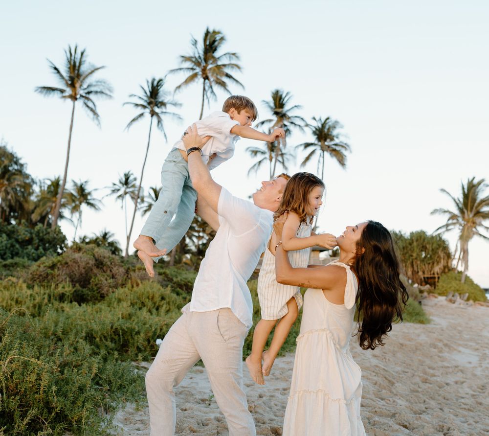 A family photoshoot by Moments With Kell on Oahu in Hawaii with family playing on the beach