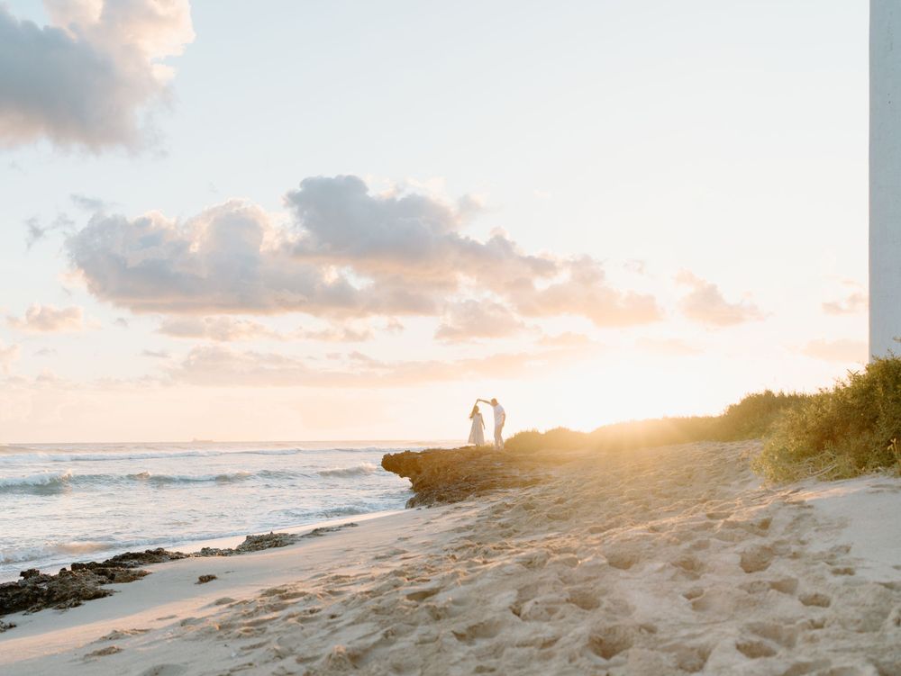 A couples photoshoot by Moments With Kell on Oahu in Hawaii with husband and wife dancing on the beach