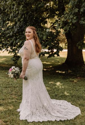 An elegant bridal portrait showcasing a detailed lace wedding gown in a garden setting.