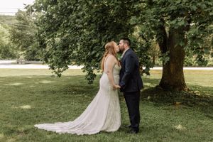 An intimate wedding moment captured in a natural outdoor setting with dappled sunlight.