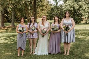 Outdoor wedding party portrait with bridesmaids wearing mix-and-match purple dresses.
