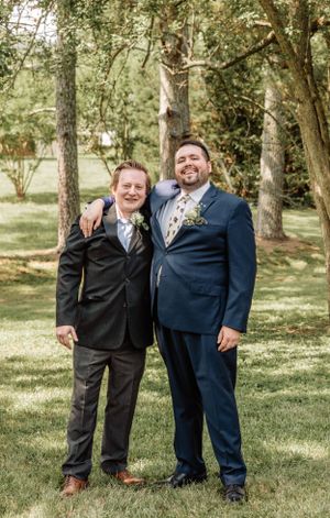 Wedding party members share laughs while posing for casual photos in a park setting.