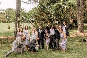 Bridal party relaxes on lawn during outdoor summer wedding photography.
