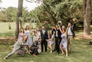 Candid moments captured as wedding party interacts outdoors in natural setting.