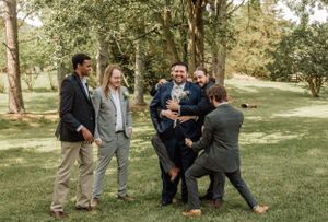 Groomsmen playfully posing and interacting outdoors during wedding photo session.