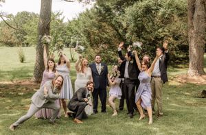 Bridal party enjoys candid photo session in rustic outdoor wedding venue.