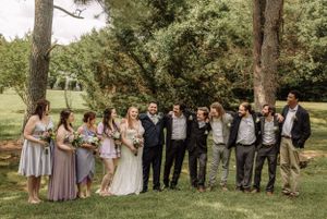 Wedding group portrait taken in natural outdoor setting with mixed formal attire.