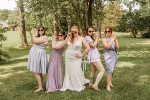 Bridesmaids in pastel dresses strike playful poses while pretending to talk on phones.