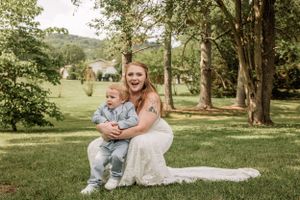 Wedding party poses for outdoor portraits in a grassy park setting with trees in the background.