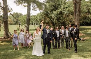 Wedding celebration group poses informally in scenic outdoor park setting.
