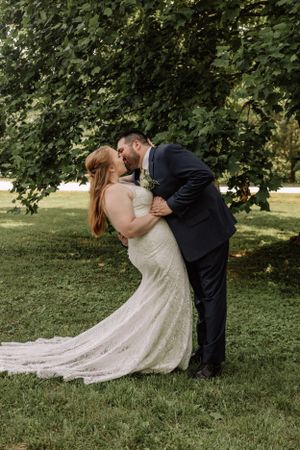 Wedding couple performs romantic dip kiss pose series in outdoor garden setting.