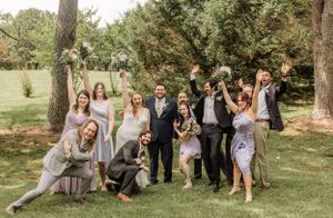 Wedding group arranges themselves for casual outdoor photography session.