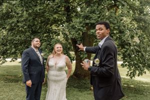 Wedding couple shares joyful moments during outdoor photo session under green trees.