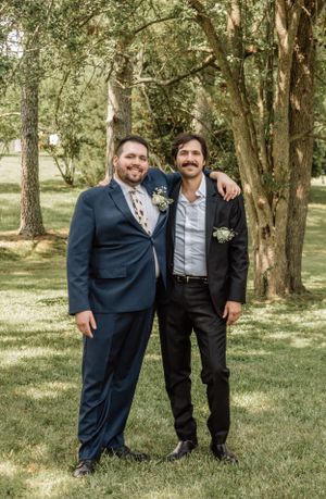 Groomsmen share friendly embraces while posing for outdoor wedding photos.