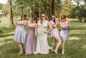 Wedding party members in coordinated lavender and blue dresses pose outdoors.