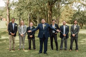 Groomsmen in dark suits and ties stand together for outdoor wedding photography.