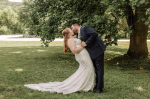 Couple in formal attire sharing an intimate moment under trees during outdoor wedding photoshoot.