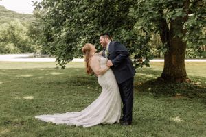 A wedding couple shares a romantic pose under a tree on their special day.