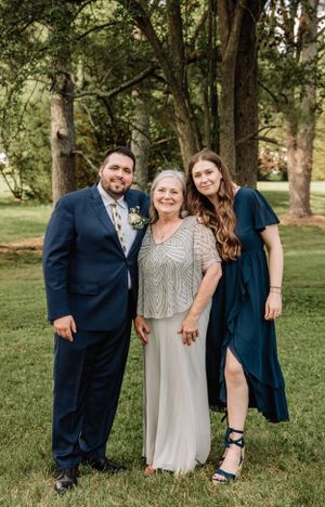 Wedding party poses in wooded area wearing mix of formal attire in navy and silver.
