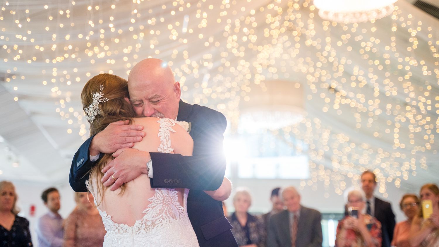 Father of the bride embraces her, shedding tears during the father-daughter dance.
