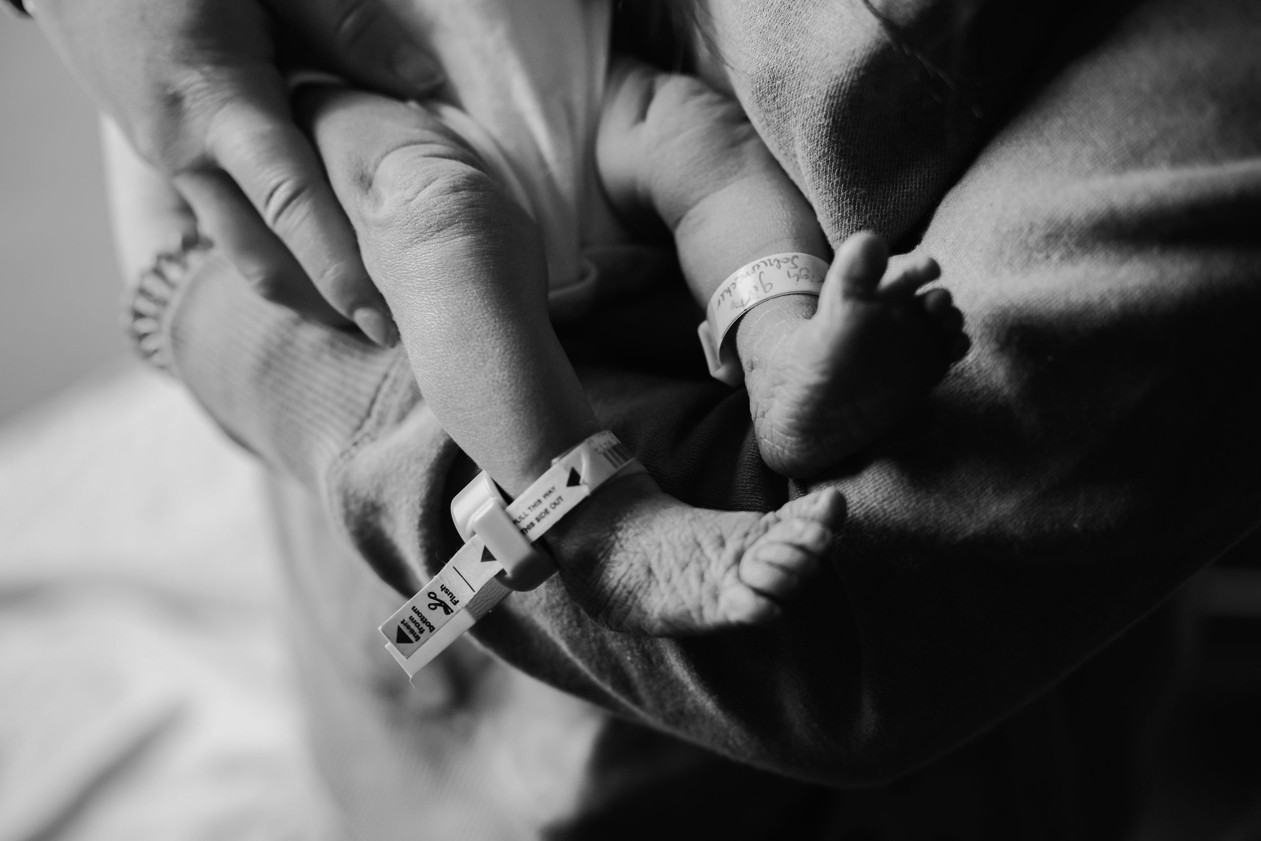 Close-up black and white image of tiny infant feet being measured.