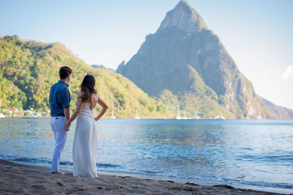 Couple walking along beach with dramatic mountain peaks and ocean views in Saint Lucia.