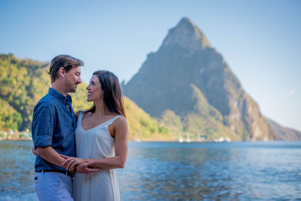 Couple embracing on beach with Pitons mountains and Caribbean waters in background.