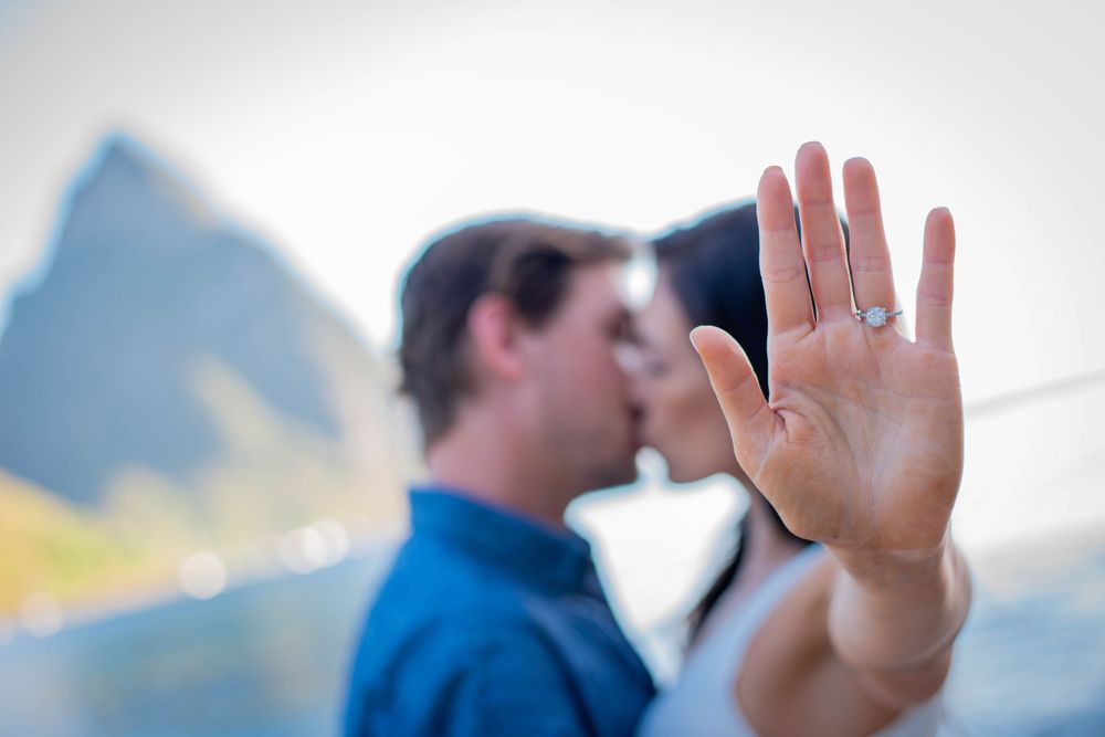 A hand raised in front of a blurred figure wearing blue against a bright background.