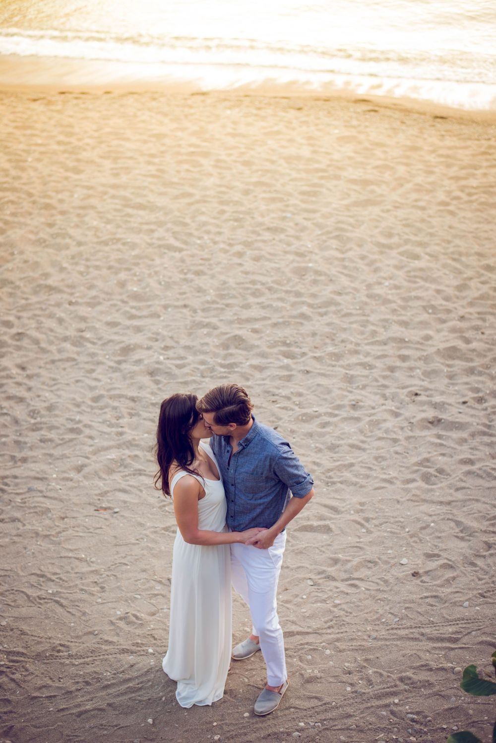 A romantic moment captured on a sandy beach during golden hour.