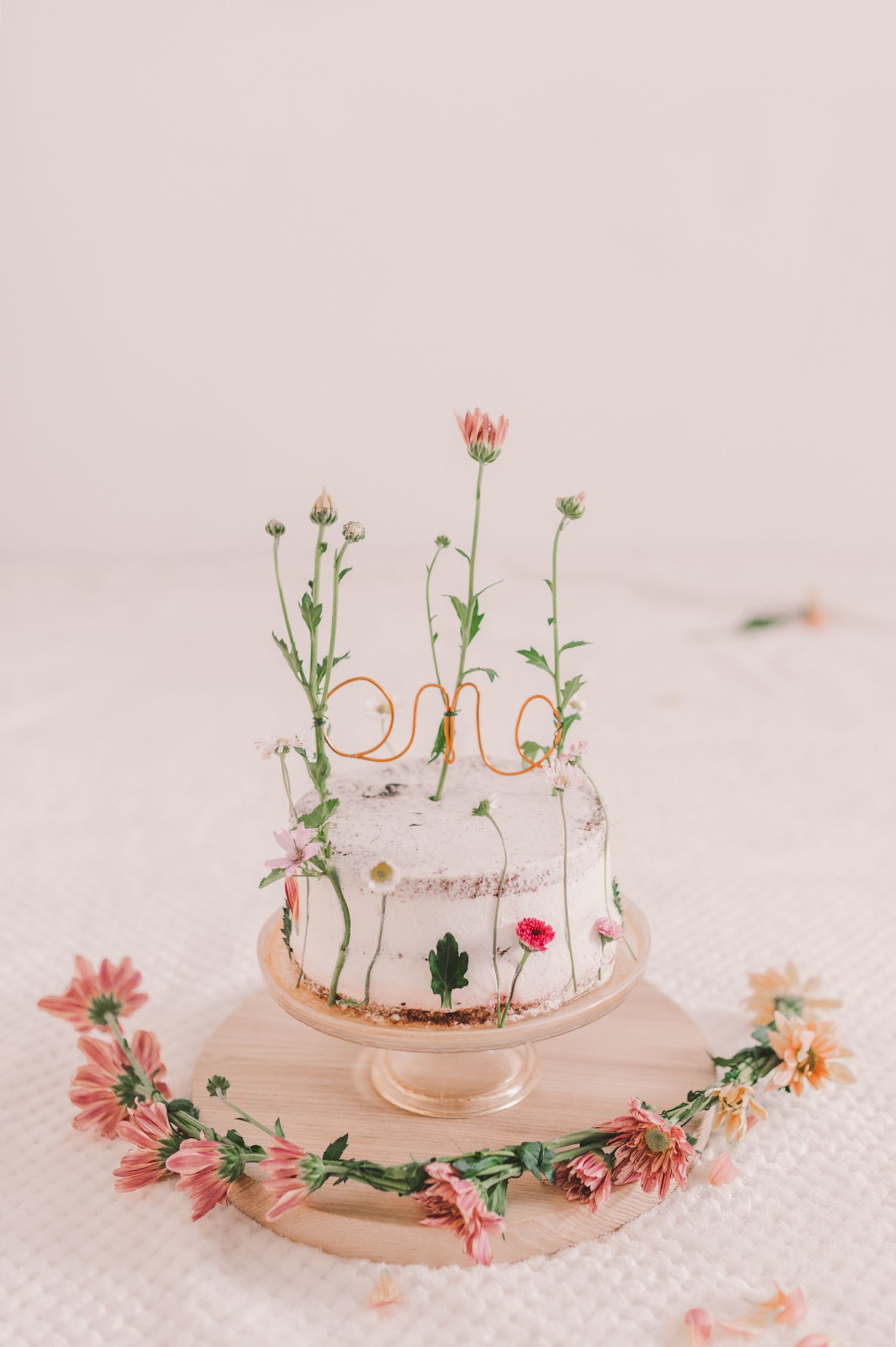 Decorative cake stand adorned with pink flowers and wire text decoration.
