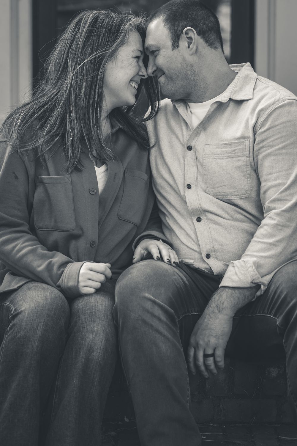 Happy couple laughing together in a black and white romantic portrait photo.