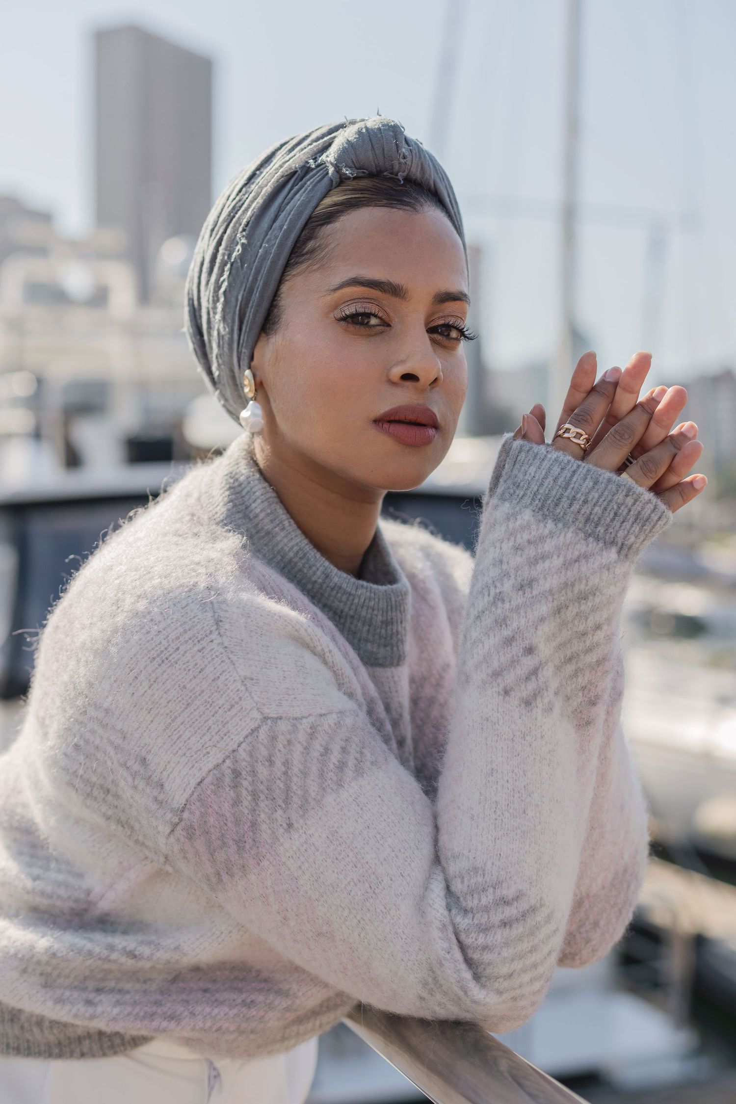 Winter fashion portrait with cozy sweater and head wrap against marina backdrop.